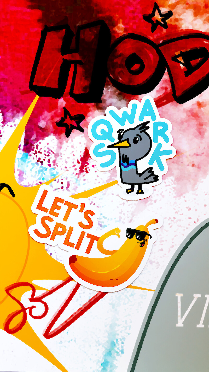 Mockup of Pictoplasma #stickycharacter sticker designs featuring a cartoon pigeon sticker with SQWARK text and a cool banana character sticker wearing sunglasses with LET'S SPLIT text on a vibrant, colourful art background.